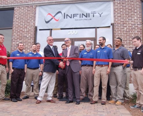 Chuck and David Brown with Infinity, Inc. staff cutting red ribbon