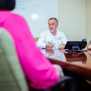 man at conference table speaking with man and woman