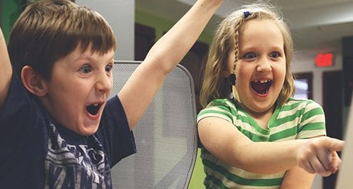 kids smiling at computer because when technology companies compete, community wins