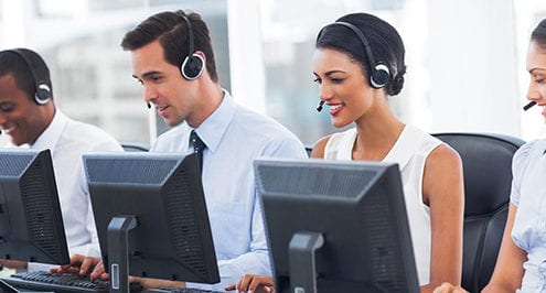 smiling professionals with headsets and computers
