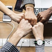 hands fistbumping over laptops for untapped power of teams