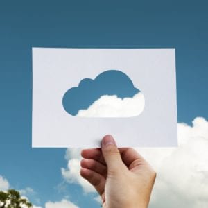hand holding a cloud cutout against blue sky